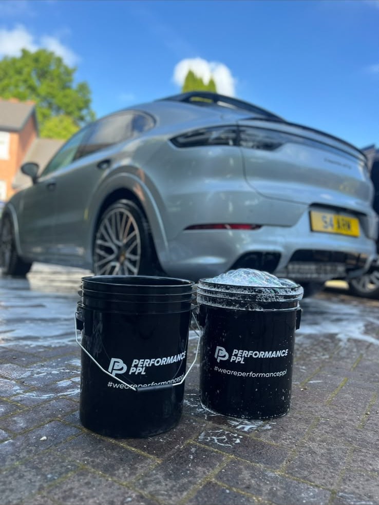 Two bucket safe wash setup beside a grey Porsche Cayenne being valeted
