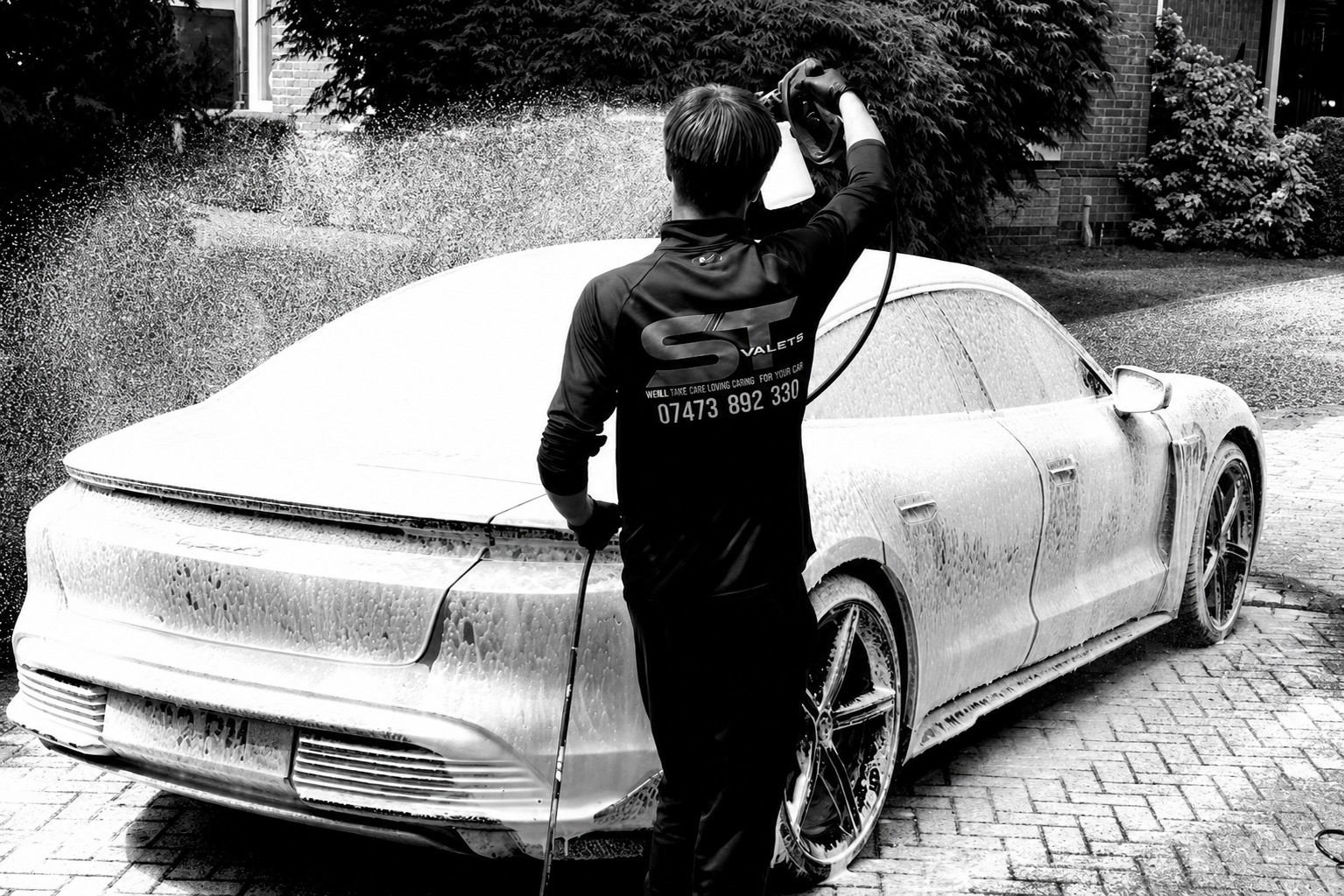 ST Valets detailer applying snow foam to a Porsche on a driveway